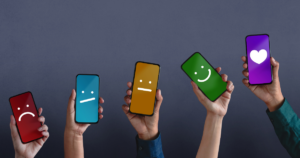 5 cell phones with different options for a feedback survey, ranging from a sad face to a heart